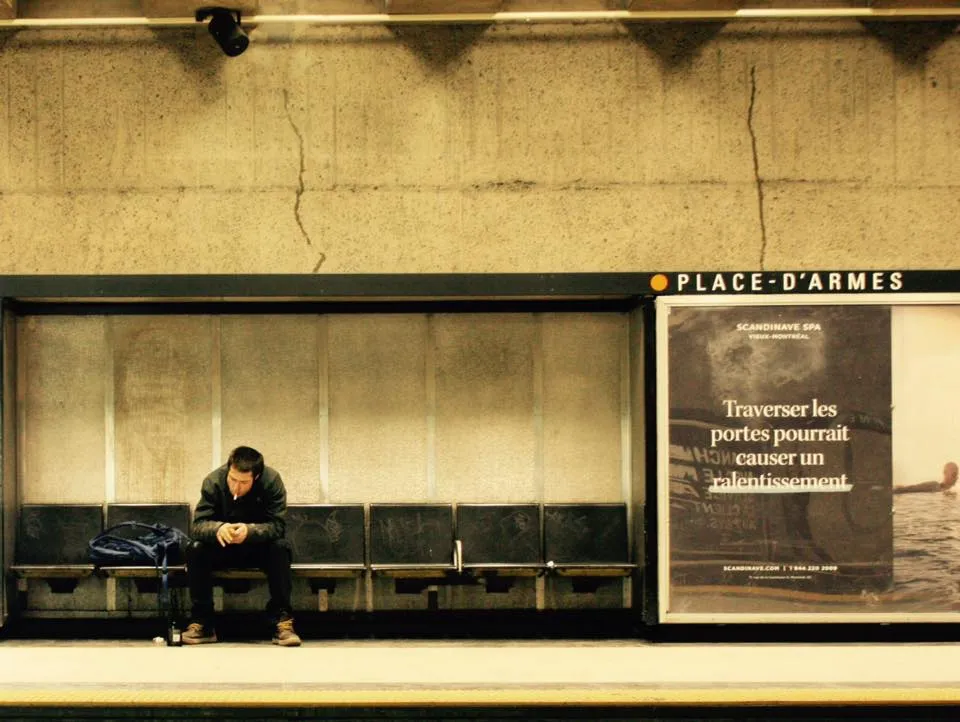 Un homme assis seul sur un banc de la station Place-d’Armes
